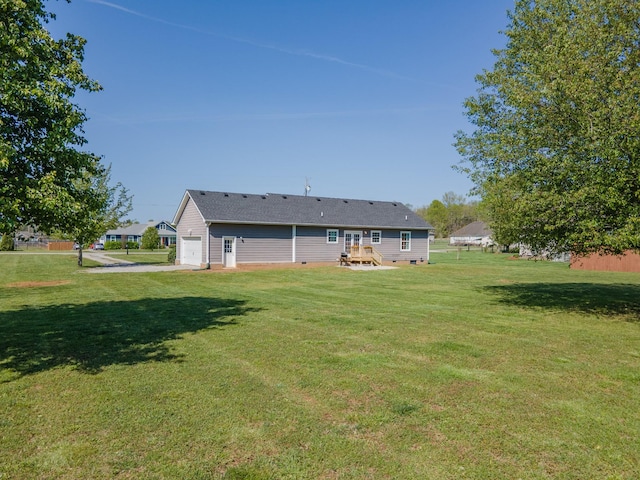 back of property featuring a garage, a deck, crawl space, and a lawn