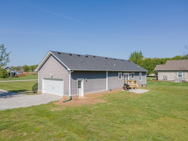 rear view of house featuring a shingled roof, a yard, crawl space, a garage, and gravel driveway