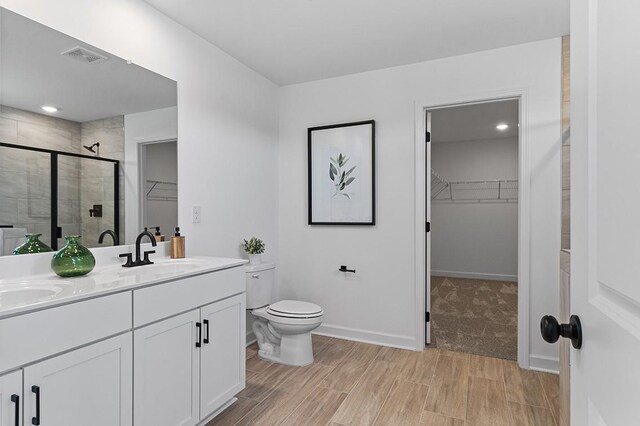 8524 Turnbull Dr, Pleasant View, TN 37146 - bathroom with a walk in closet, a stall shower, double vanity, toilet, and wood finish floors