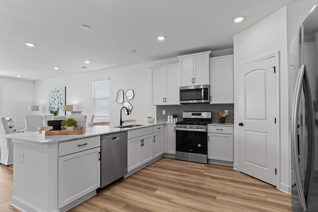 8524 Turnbull Dr, Pleasant View, TN 37146 - kitchen featuring appliances with stainless steel finishes, a sink, a peninsula, decorative backsplash, and white cabinetry