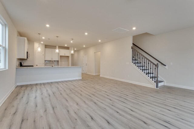8583 Turnbull Dr, Pleasant View, TN 37146 - unfurnished living room with baseboards, a sink, light wood finished floors, recessed lighting, and stairs