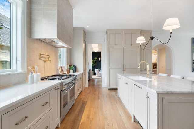 2109 10th Ave S, Nashville, TN 37204 - kitchen with tasteful backsplash, a sink, wall chimney range hood, light wood-type flooring, and double oven range