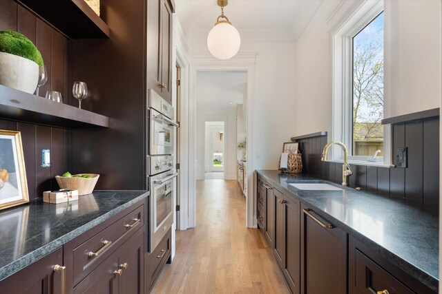 2109 10th Ave S, Nashville, TN 37204 - kitchen featuring dark stone countertops, open shelves, light wood finished floors, a sink, and hanging light fixtures