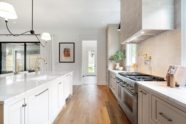 2109 10th Ave S, Nashville, TN 37204 - kitchen with light wood-style floors, tasteful backsplash, wall chimney range hood, a sink, and range with two ovens