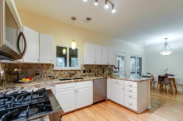 kitchen with a peninsula, white cabinetry, visible vents, appliances with stainless steel finishes, and a sink