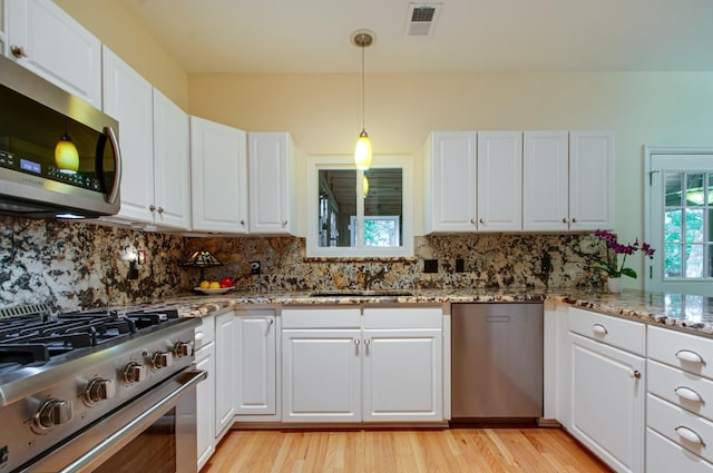 kitchen featuring white cabinetry, visible vents, decorative backsplash, stainless steel appliances, and a sink