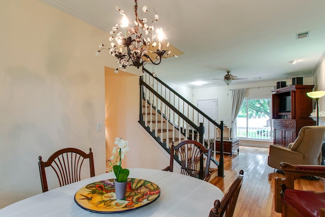 dining area featuring ornamental molding, wood-type flooring, visible vents, and ceiling fan with notable chandelier