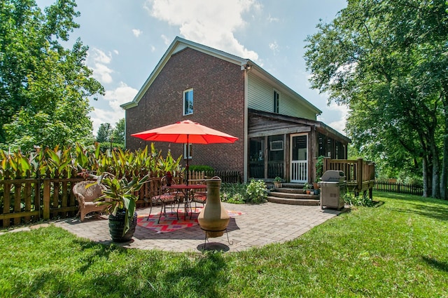 rear view of property featuring a patio, fence private yard, brick siding, a sunroom, and a lawn