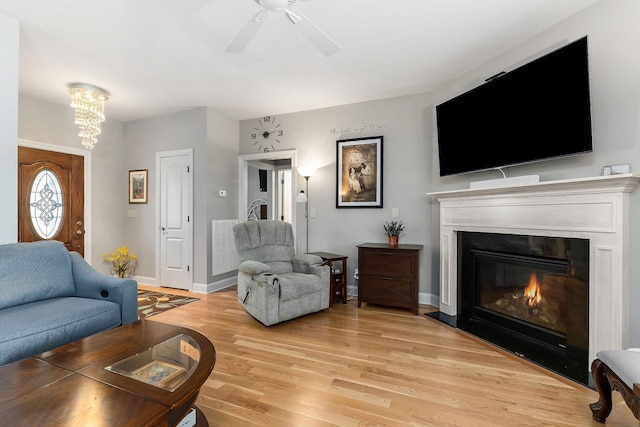 134 Joe Blanton Rd, Woodbury, TN 37190 - living room featuring a fireplace with flush hearth, light wood-style flooring, baseboards, and ceiling fan with notable chandelier