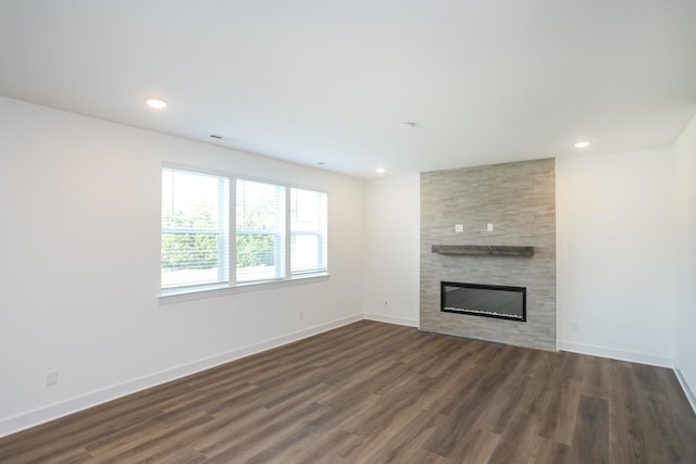 unfurnished living room with dark wood finished floors, baseboards, and a fireplace