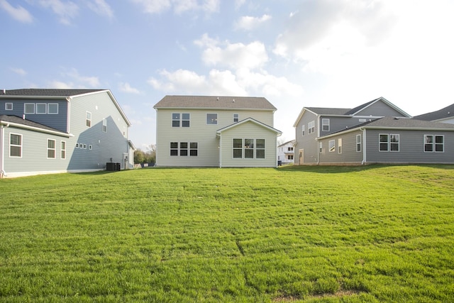 back of house featuring central air condition unit and a lawn