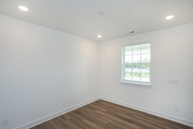 empty room featuring dark wood-style flooring, visible vents, recessed lighting, and baseboards