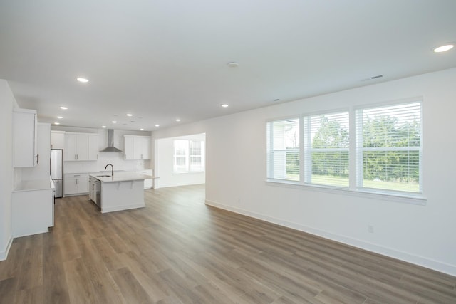 unfurnished living room with baseboards, wood finished floors, and a healthy amount of sunlight