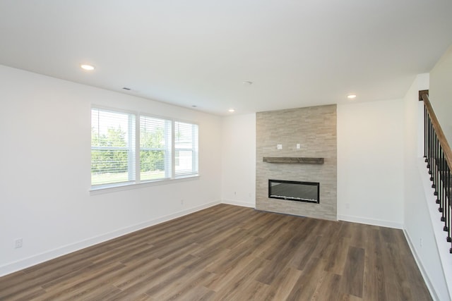 unfurnished living room featuring recessed lighting, a fireplace, stairs, baseboards, and wood finished floors