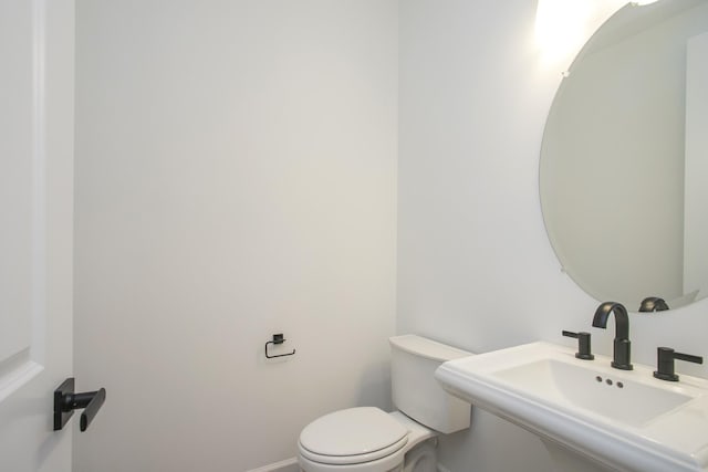 bathroom with baseboards, toilet, and a sink