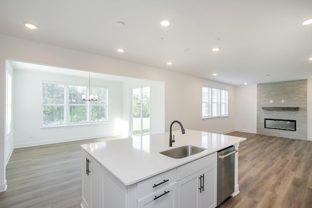 kitchen with open floor plan, dishwasher, light wood finished floors, and a sink