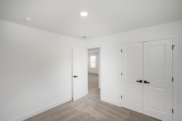 unfurnished bedroom with light colored carpet, a closet, recessed lighting, and baseboards
