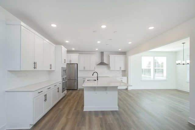 kitchen featuring a sink, appliances with stainless steel finishes, light countertops, light wood-type flooring, and wall chimney exhaust hood