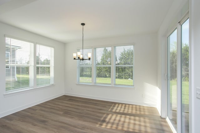 unfurnished dining area with a healthy amount of sunlight, baseboards, an inviting chandelier, and dark wood-style flooring