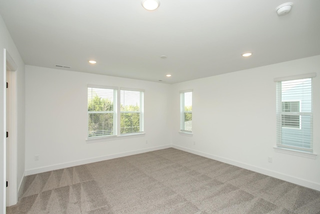 spare room featuring visible vents, recessed lighting, light colored carpet, and baseboards