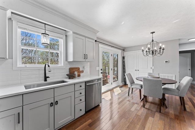 kitchen with tasteful backsplash, a chandelier, gray cabinets, dishwasher, and a sink