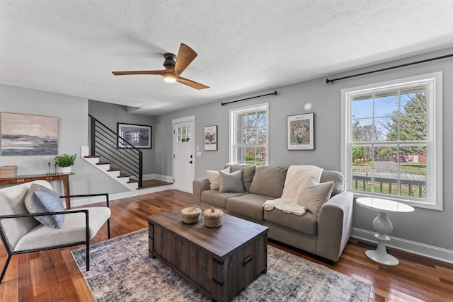 living room featuring stairs, baseboards, wood finished floors, and ceiling fan
