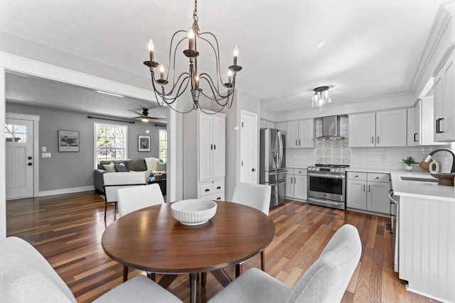 dining room with ceiling fan with notable chandelier, baseboards, and dark wood-style floors