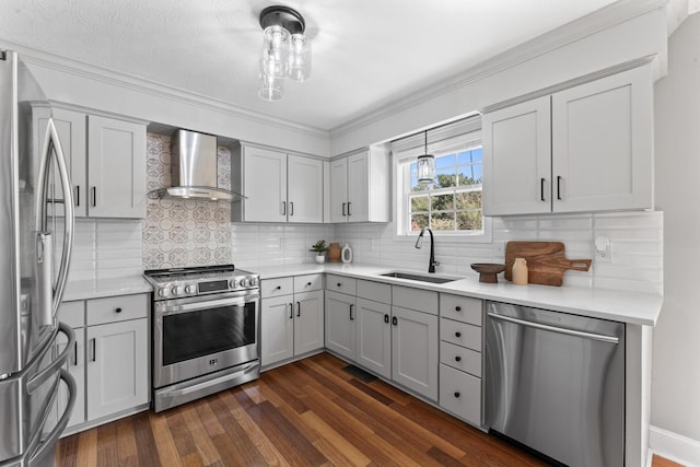 kitchen with appliances with stainless steel finishes, a sink, wall chimney range hood, and dark wood-style floors