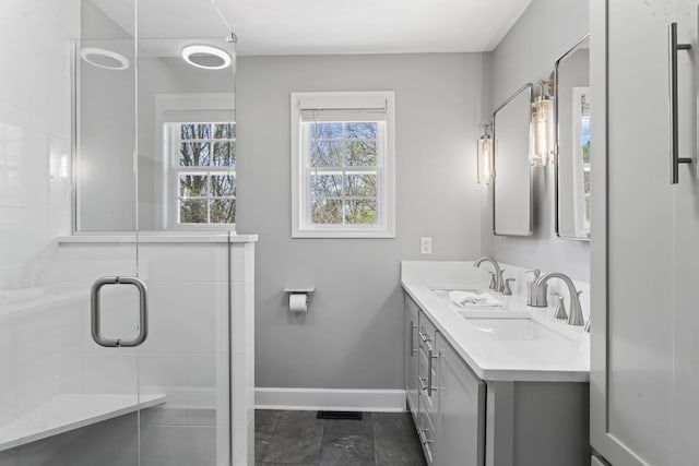 full bath featuring a sink, baseboards, double vanity, and a stall shower