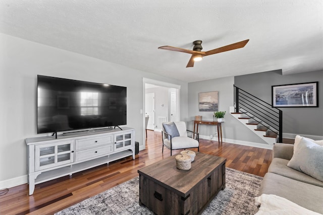living room with wood finished floors, baseboards, a ceiling fan, and stairs