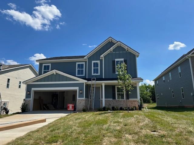 craftsman house featuring driveway, a garage, a front lawn, and board and batten siding