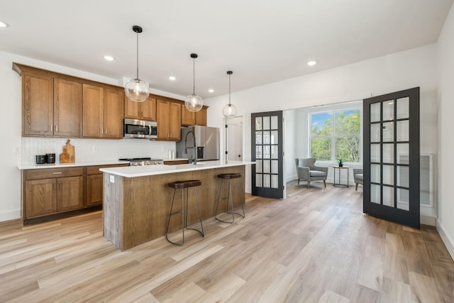 kitchen with light countertops, light wood-style floors, brown cabinetry, stainless steel appliances, and french doors