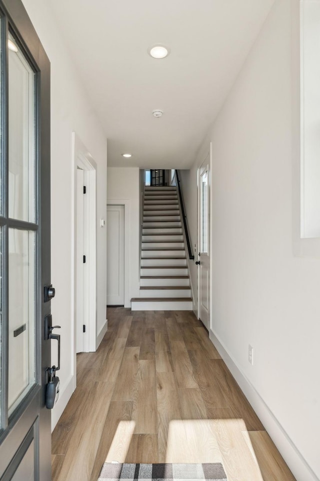 interior space with light wood finished floors, baseboards, recessed lighting, and stairway