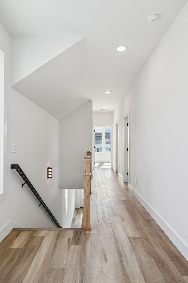 hall with recessed lighting, an upstairs landing, baseboards, and wood finished floors