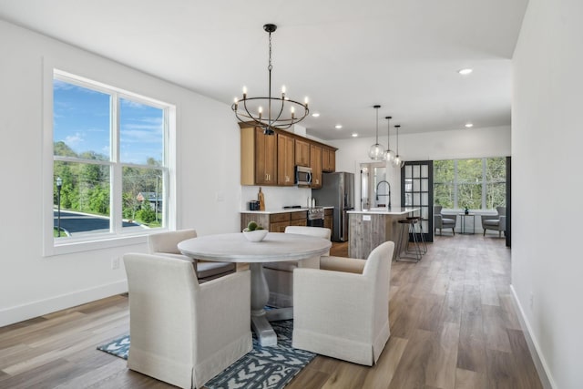 dining space with a notable chandelier, baseboards, and light wood-style flooring