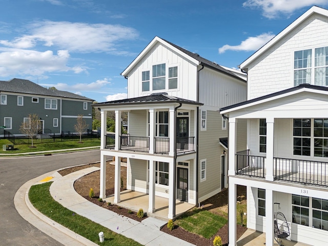 view of front facade featuring board and batten siding, metal roof, a patio, and a balcony