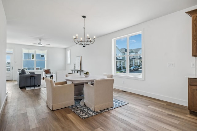 dining area featuring light wood-type flooring, baseboards, and ceiling fan with notable chandelier