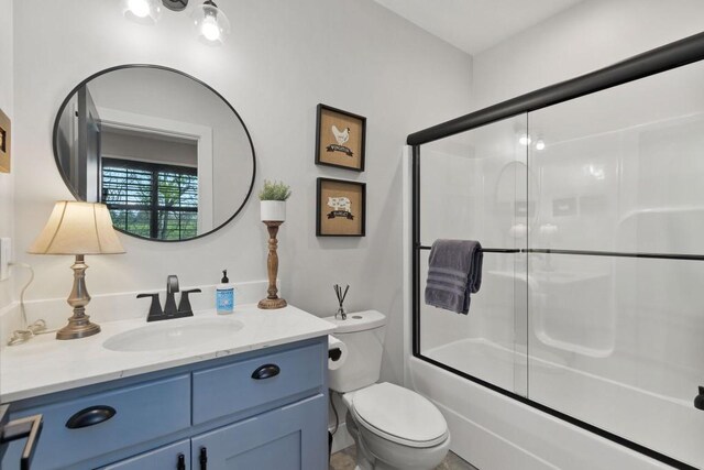 full bathroom featuring enclosed tub / shower combo, vanity, and toilet
