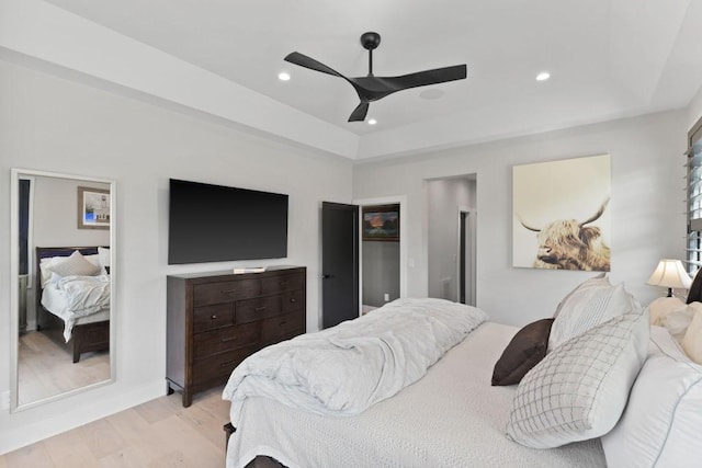bedroom with ceiling fan, light wood finished floors, a raised ceiling, and recessed lighting