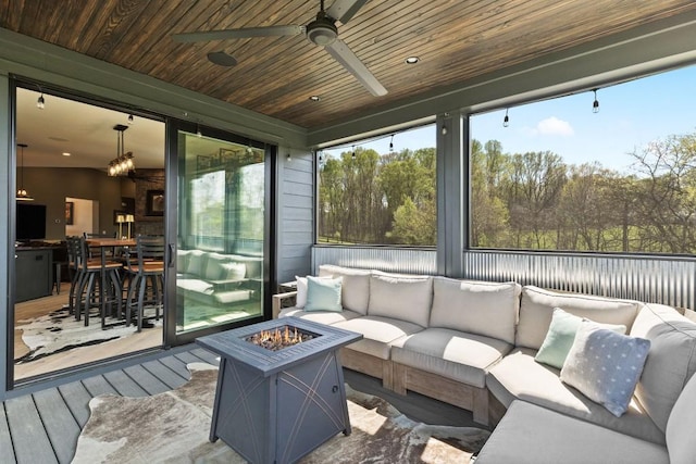 sunroom with an outdoor living space with a fire pit and a ceiling fan