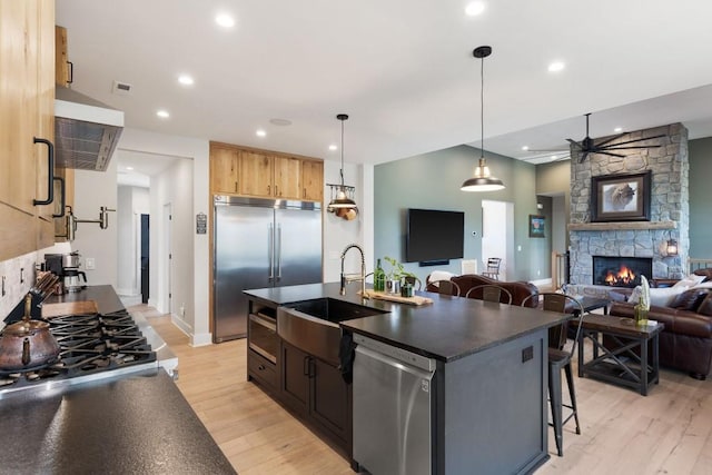 kitchen with open floor plan, dark countertops, light wood-style floors, a fireplace, and stainless steel appliances