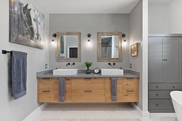 full bath with a freestanding tub, double vanity, baseboards, and a sink