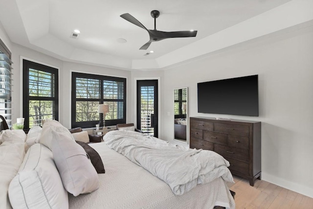 bedroom with a ceiling fan, recessed lighting, a raised ceiling, light wood finished floors, and baseboards