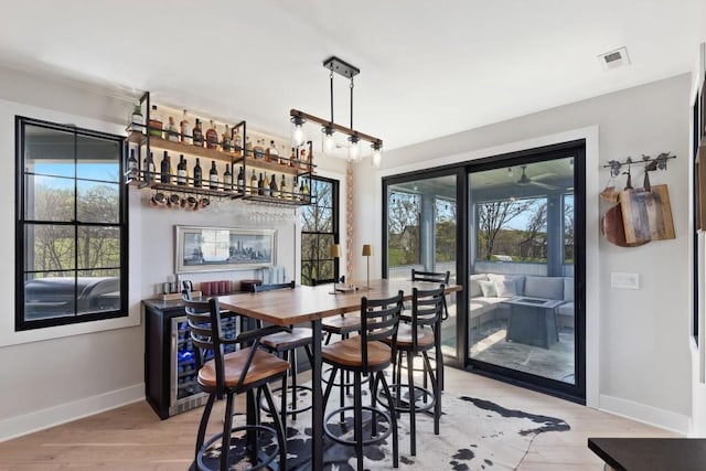 dining area featuring light wood-style flooring, baseboards, and a healthy amount of sunlight