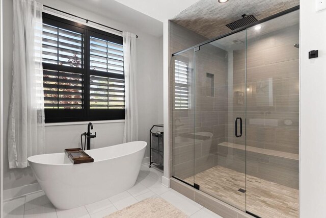full bathroom with tile patterned floors, a freestanding tub, baseboards, and a stall shower