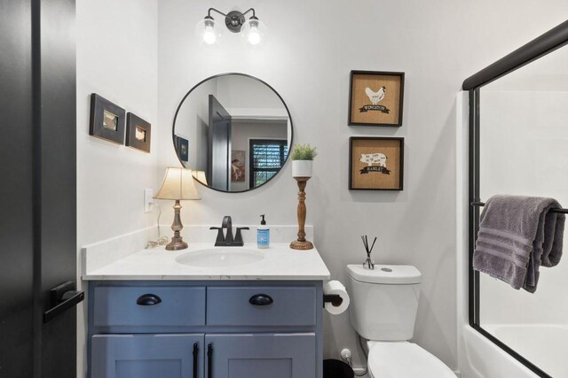 bathroom with toilet, vanity, and bath / shower combo with glass door