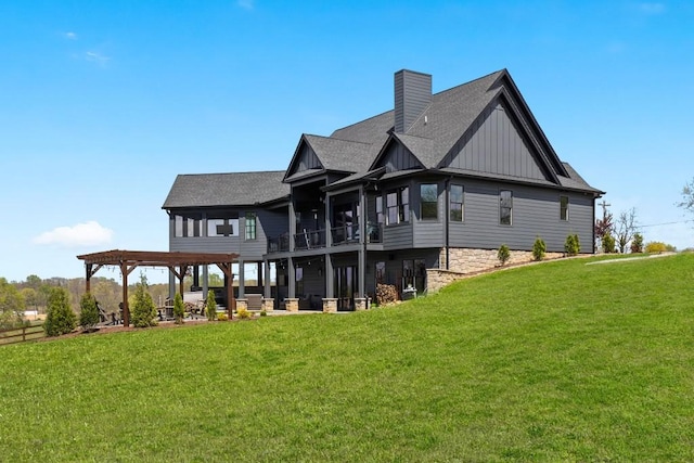 rear view of house with board and batten siding, a chimney, a lawn, and roof with shingles