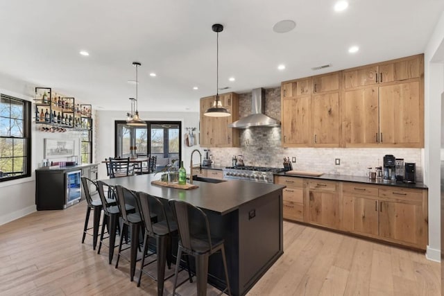 kitchen with decorative backsplash, wall chimney exhaust hood, a sink, and dark countertops