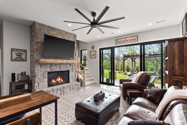 living room with visible vents, ceiling fan, a stone fireplace, and recessed lighting