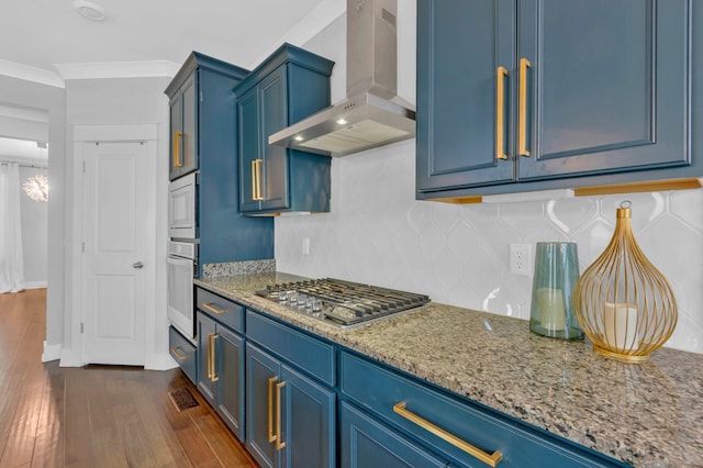 779 Newcomb St, Franklin, TN 37064 - kitchen featuring wall chimney exhaust hood, blue cabinetry, appliances with stainless steel finishes, dark wood-style floors, and crown molding